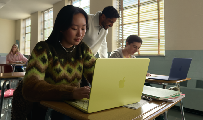 Estudiante utilizando un MacBook Neo, color cítrico, portátil sin enchufar en un aula